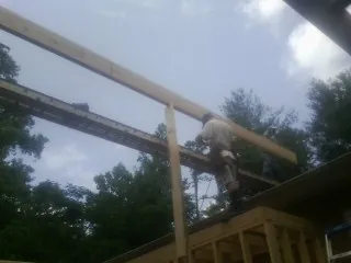Carpenter setting a ridge beam over a new addition frame — Ice Dam Removal by Roofing Brothers in Parmele