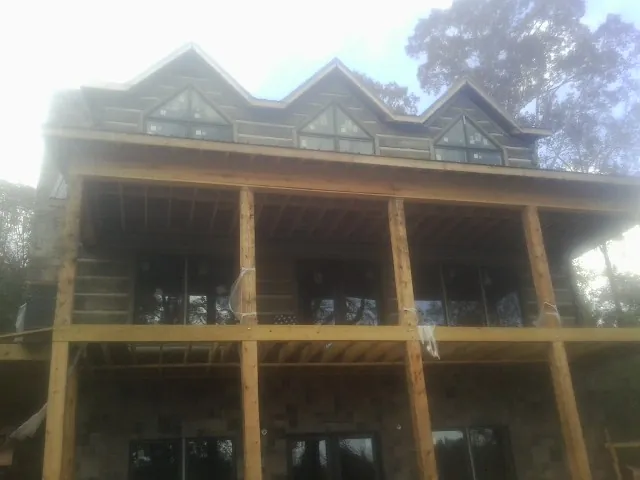 Dormers and porch framing on a large log home under construction — Roof Coating work by our crew in Parmele