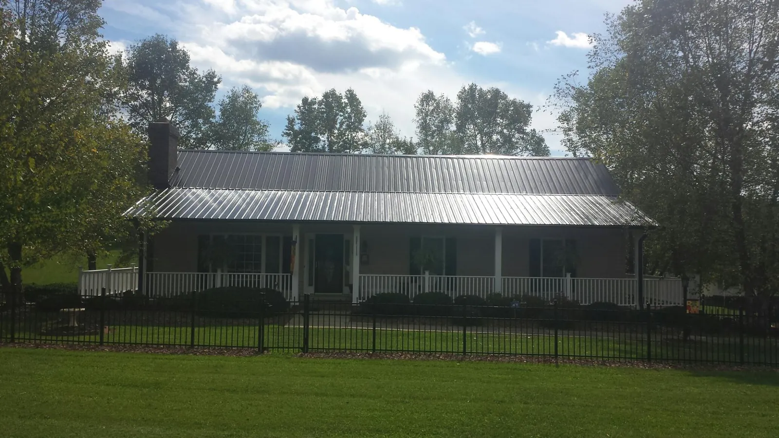 Gray metal roof on a brick ranch with a full width front porch — Gutter Guard Installation work by our crew in Parmele