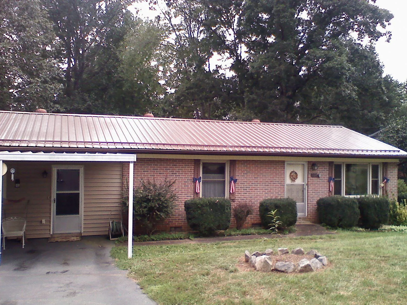 Bronze metal roof and carport on a brick ranch home — Roof Repair work by our crew in Parmele