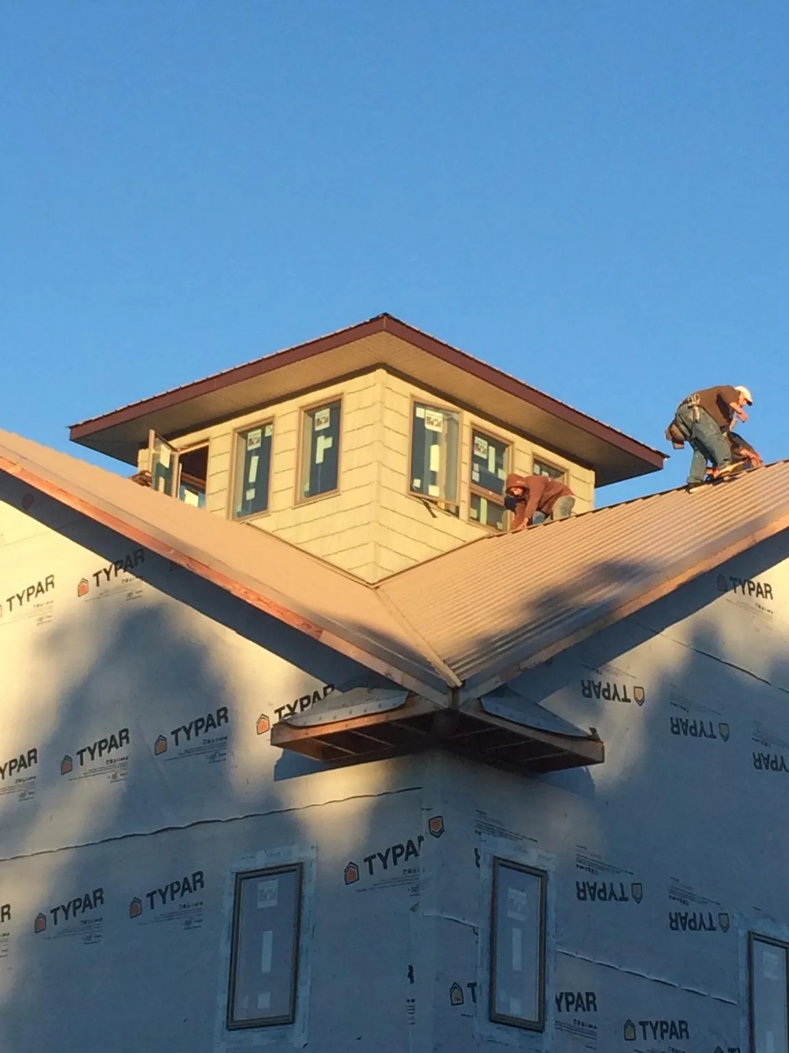 Roofers working around a rooftop cupola on a new metal roof at sunset — Roof Waterproofing in Parmele by Roofing Brothers